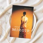 Livre Devant le miroir de Marie-Eve Matte, posé sur une assiette blanche avec une nappe en tissu et quelques fleurs séchées, évoquant douceur et introspection