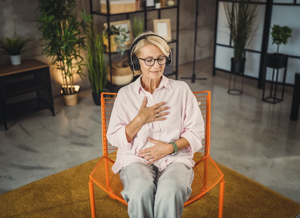 Femme en pleine respiration consciente, yeux fermés, en posture de détente, illustrant la cohérence cardiaque