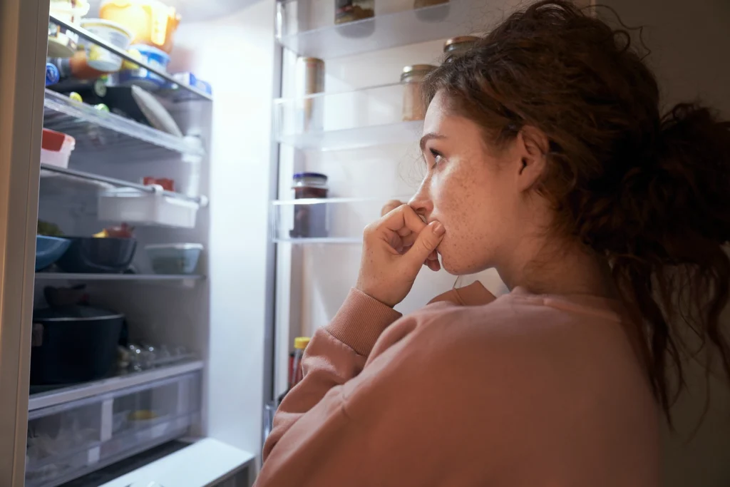 Femme devant le frigo, indécise. 